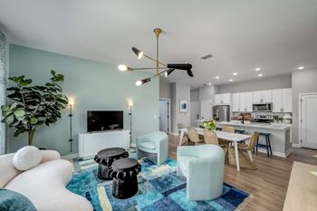 a living room with a couch a table and a chair and a kitchen in the background at Ironwood Flats, Brandon